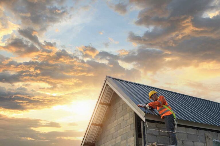 A residential roof displays asphalt shingles, metal panels, and slate samples beside snow-covered roofing tools.