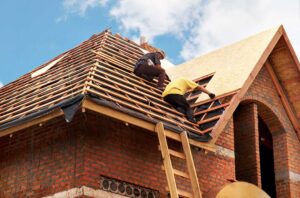 Homeowner inspecting roof shingles from the ground beside a house with clear gutters and downspouts.