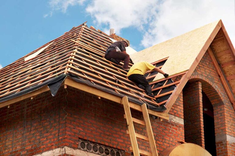 Homeowner inspecting roof shingles from the ground beside a house with clear gutters and downspouts.