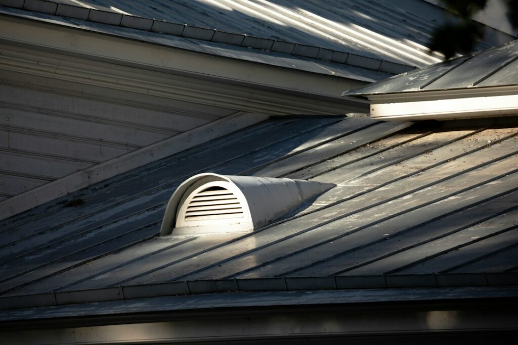 An attic with clean insulation, visible rafter baffles, and daylight entering through soffit ventilation channels.